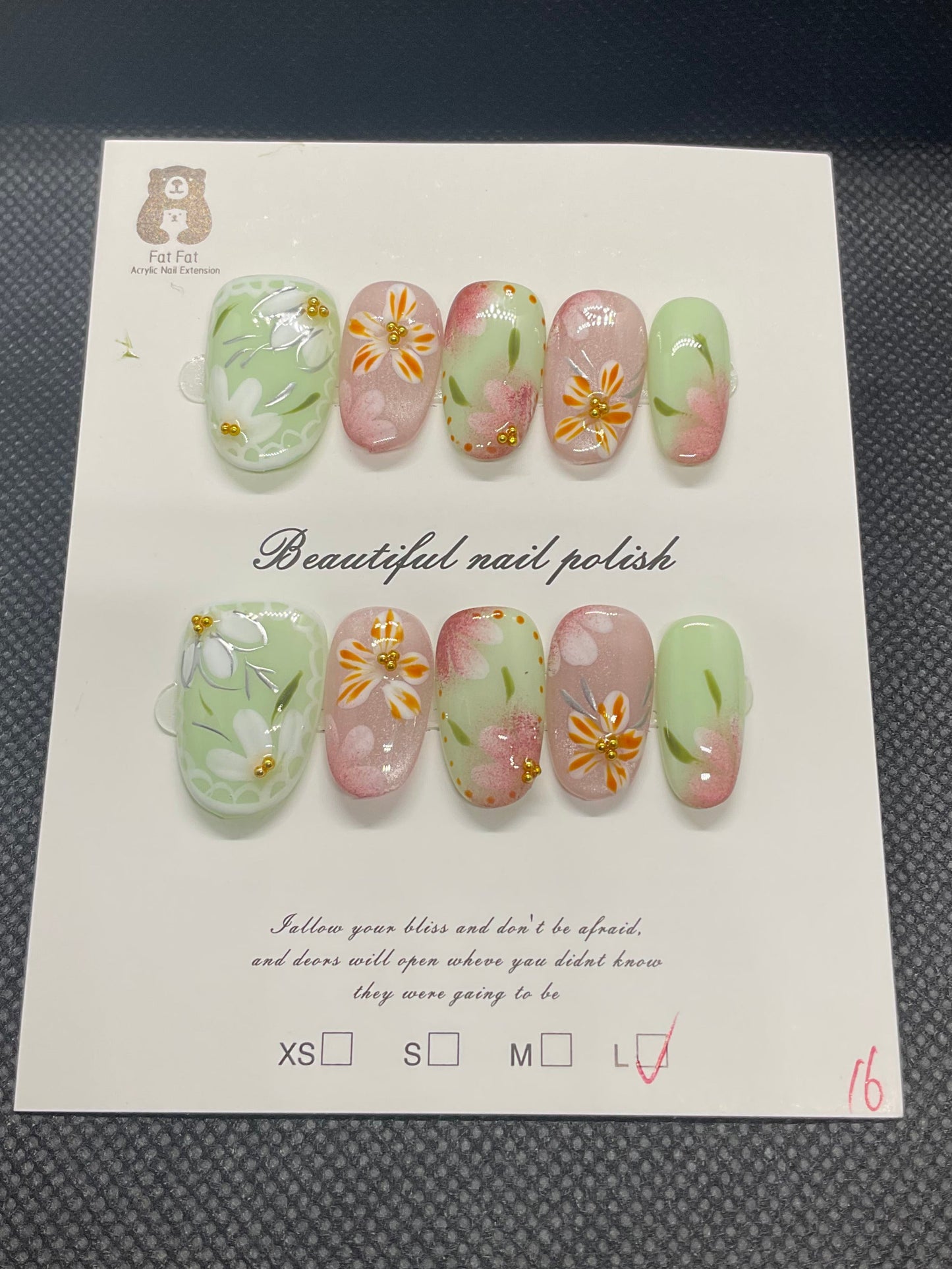 Green and pink almond press-on nails with hand-painted floral accents and subtle shimmer. 