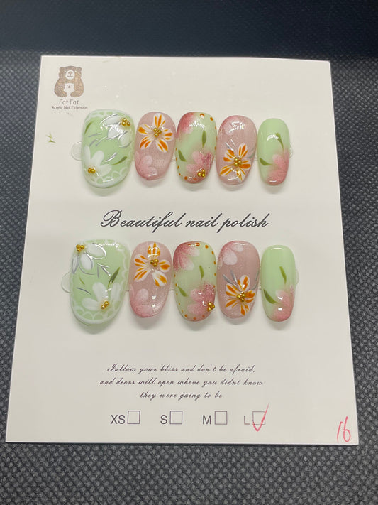 Green and pink almond press-on nails with hand-painted floral accents and subtle shimmer. 