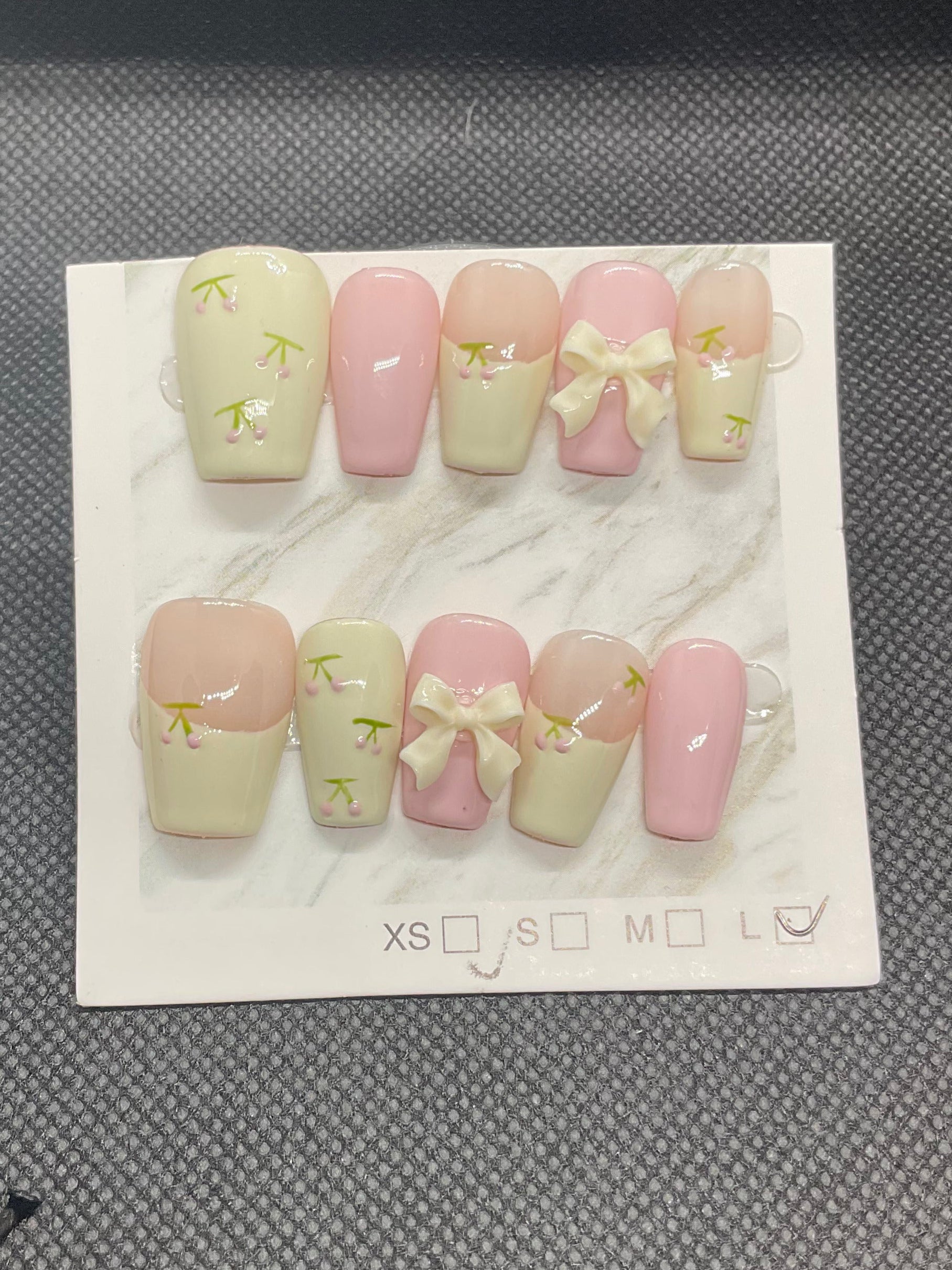 Soft pink and cream press-on nails featuring delicate floral accents and a statement 3D bow.