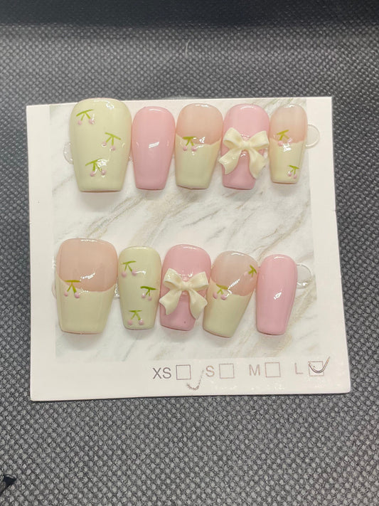 Soft pink and cream press-on nails featuring delicate floral accents and a statement 3D bow.